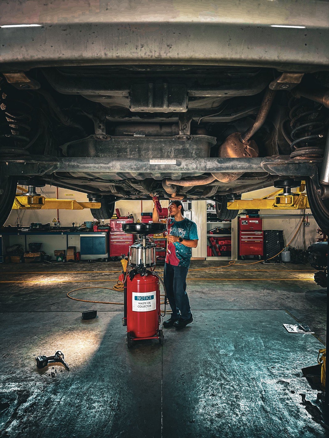 Technician working beneath a vehicle on a hoist in a Hamilton repair shop