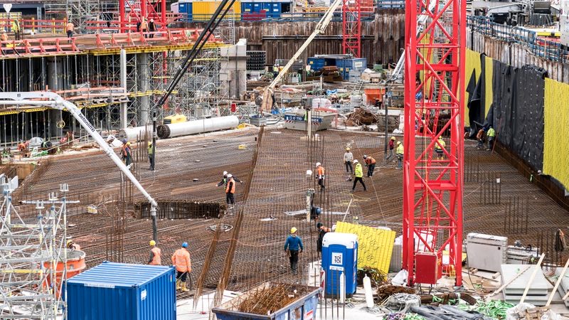 Workers laying out concrete reinforcement on a large construction site